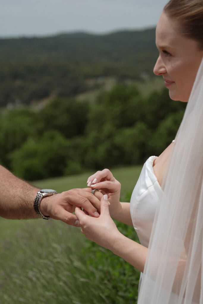 Close-up of bride placing groom's wedding band on finger.