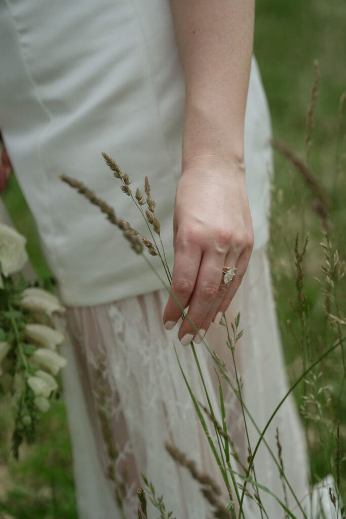 Bride grasps grass as her wedding band is on display.