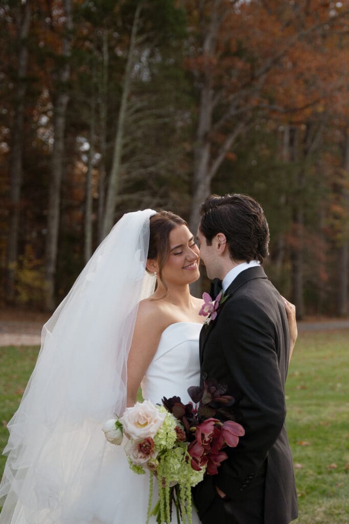 Couple smile intimately close during their outdoor wedding photos.